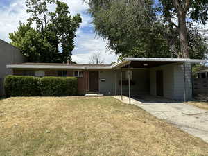 Single story home featuring a front yard and a carport