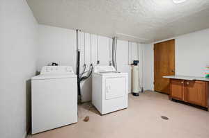 Clothes washing area featuring washer and dryer and a textured ceiling