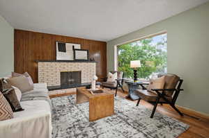 Living room with a fireplace, wood-type flooring, and wooden walls