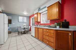 Kitchen featuring white appliances, sink, and light tile patterned floors