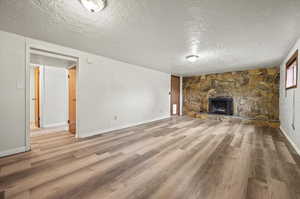 Unfurnished living room with a textured ceiling, a fireplace, and hardwood / wood-style flooring