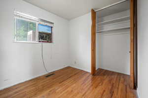 Unfurnished bedroom with hardwood / wood-style floors and a closet