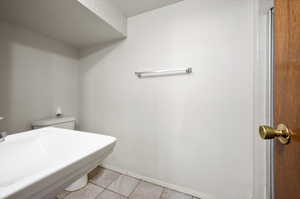 Bathroom with toilet, tile patterned floors, and sink and shower