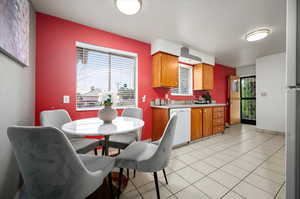 Kitchen featuring light tile patterned floors, sink, dishwasher, and plenty of natural light