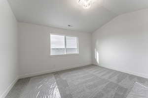 Spare room with light carpet and vaulted ceiling