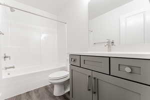 Full bathroom featuring vanity, hardwood / wood-style floors,  shower combination, and toilet