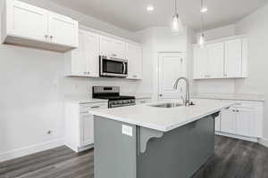 Kitchen with white cabinetry, an island with sink, and stainless steel appliances