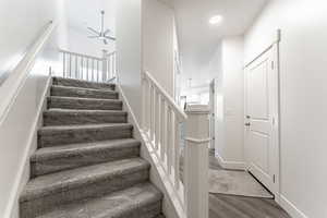 Staircase with ceiling fan and wood-type flooring