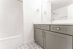 Full bathroom with tile patterned floors, vanity, shower / washtub combination, baseboards, and visible vents