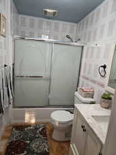 Full bathroom with toilet, bath / shower combo with glass door, vanity, and tile patterned flooring