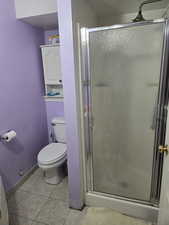 Bathroom #2 with a shower with door, tile patterned flooring, and toilet