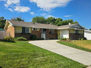 Single story home featuring a garage and a front yard