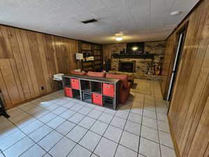 Recreation room with wood walls, brick wall, a brick fireplace, and tile patterned flooring