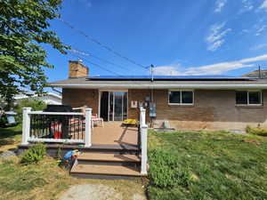 Rear view of house featuring a lawn and a wooden deck