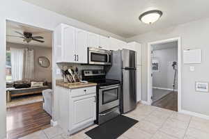 Kitchen featuring light hardwood / wood-style flooring, stainless steel appliances, ceiling fan, and white cabinetry