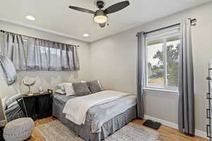 Bedroom with ceiling fan, light hardwood / wood-style flooring, and multiple windows