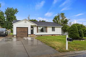 Ranch-style house with a garage and a front lawn