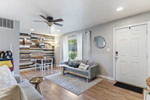 Living room featuring ceiling fan, wood walls, and light hardwood / wood-style floors