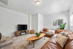 Living room with a textured ceiling and light colored carpet