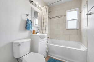 Full bathroom with toilet, shower / tub combo with curtain, and vanity