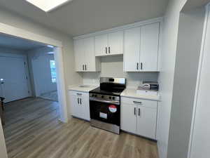 Kitchen with electric range, white cabinets, and light hardwood / wood-style floors