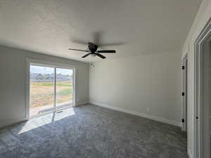 Spare room featuring a textured ceiling, carpet, and ceiling fan