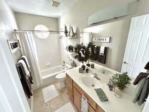 Main Floor Full bathroom featuring shower / tub combo, a textured ceiling, toilet, tile patterned floors, and vanity