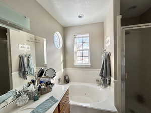 Master Bathroom with vanity, a textured ceiling, and independent shower and jacuzzi bath