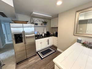 Kitchen with white cabinets, sink, wood-type flooring, and stainless steel fridge