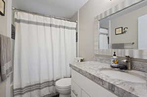 Bathroom with a textured ceiling, vanity, and toilet