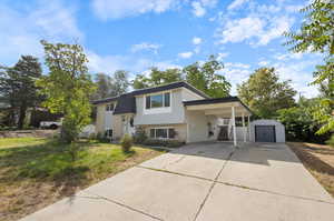 Bi-level home featuring a storage unit, a carport, and a front yard