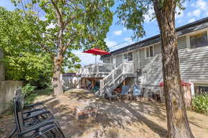 Rear view of house featuring a wooden deck, cooling unit, and a patio