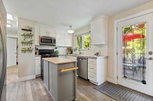 Kitchen featuring appliances with stainless steel finishes, butcher block counters, light hardwood / wood-style flooring, and a center island