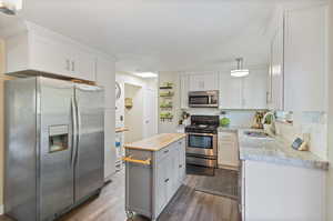 Kitchen featuring backsplash, a kitchen island, wood-type flooring, sink, and stainless steel appliances