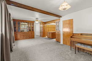 Interior space featuring wood built in cabinets, ceiling fan, and ceiling beam