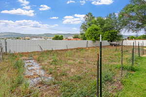 View of yard with a mountain view, garden space, fence is within the front half acre