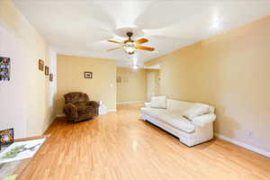 Living room with ceiling fan and light hardwood / wood-style floors