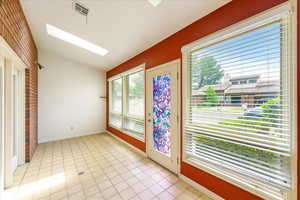 Entryway featuring a skylight, light tile patterned floors, and brick wall