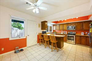 Kitchen featuring stainless steel appliances, a kitchen bar, ceiling fan, sink, and kitchen peninsula