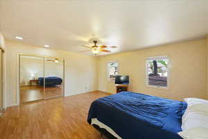 Bedroom featuring ceiling fan, light hardwood / wood-style floors, and a closet