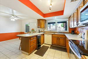 Kitchen featuring kitchen peninsula, white dishwasher, a breakfast bar, and a wealth of natural light