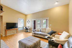 Living room featuring light hardwood / wood-style flooring, lofted ceiling, and a wealth of natural light