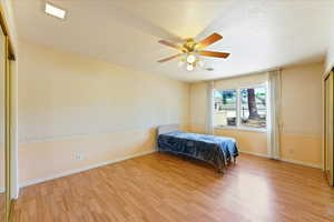 Bedroom featuring ceiling fan, a textured ceiling, a closet, and light hardwood / wood-style floors