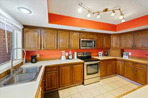 Kitchen with rail lighting, light tile patterned flooring, stainless steel appliances, and sink