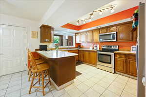 Kitchen featuring stainless steel appliances, a kitchen breakfast bar, sink, rail lighting, and kitchen peninsula