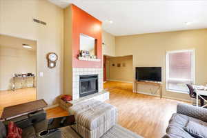 Living room featuring a tile fireplace, high vaulted ceiling, and light wood-type flooring