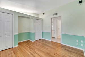 Unfurnished bedroom with multiple closets and light wood-type flooring