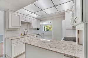 Kitchen with a drop ceiling, sink, light tile patterned flooring, and backsplash