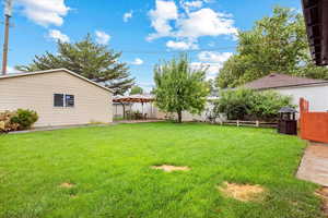 View of the back yard and garden area with pear tree and showing the custom gate that leads to the driveway.