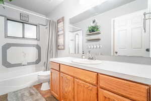 Full bathroom featuring shower / bathtub combination with curtain, toilet, tile patterned floors, and vanity